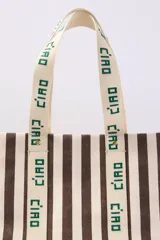 Bolso tote de lona a rayas verticales marrones y blancas con asas de mano y estampado "Ciao" en las asas.