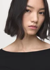 Remera negra de manga larga con cuello barco, confeccionada en tejido elástico y entallado.
