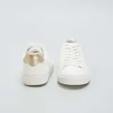 Zapatillas bajas blancas de cuero sintético con cordones y detalle en color beige en el talón.