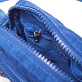 Bandolera pequeña color azul, confeccionada en material textil con acabado arrugado. Cuenta con un compartimento principal con cierre, un bolsillo frontal con cierre, correa ajustable con logo grabado y parche circular con el logo de la marca en el frente.