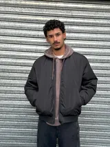 Campera bomber negra de nylon con cierre frontal y bolsillos laterales.