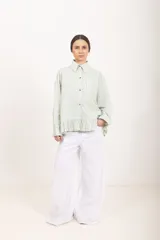 Camisa de manga larga a rayas blancas y verdes, con cuello clásico, cierre frontal de botones y detalle de volados en el ruedo.