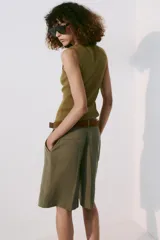 Bermuda fluida color verde militar con pinzas delanteras, tiro medio y trabillas en la cintura. Incluye un cinturón marrón de gamuza con hebilla metálica dorada.