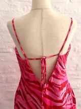 Vestido corto ajustado color rosa con estampado animal print en tonos fucsia y rosa más claro. Presenta escote drapeado tipo cowl neck y tirantes finos ajustables.