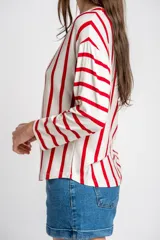 Remeron de corte oversize con cuello redondo y mangas largas. Presenta un diseño de rayas verticales en color rojo sobre base color crema.