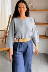 Sweater gris melange con detalles de perlas y strass aplicados en las mangas, de corte holgado y mangas largas.