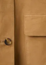 Chaqueta corta de piel caprina en color tostado, con cuello camisero, cierre frontal de botones y bolsillos de parche con solapa en el pecho.