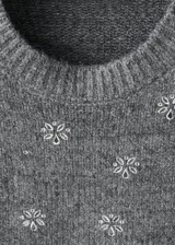 Sweater de punto fino color gris con cuello redondo, manga larga y diseño decorado con cristales brillantes distribuidos por toda la prenda.