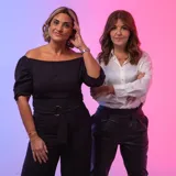 Mono largo negro con escote off-shoulder, mangas 3/4 abullonadas y cinturón con hebilla dorada.