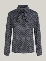 Camisa azul con estampado de rombos blancos, cuello con lazo y mangas largas.