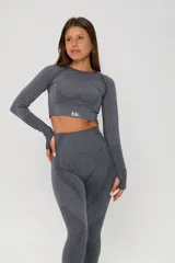 Conjunto deportivo de dos piezas compuesto por un top de manga larga tipo crop top con aberturas para pulgares y una calza de tiro alto. Ambas prendas presentan un diseño seamless con detalles de texturas perforadas y el logo de la marca estampado en el frente.