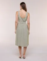 Vestido midi abotonado verde melange, con escote recto, tirantes anchos y falda de calce recto con vuelo sutil. Tiene abotonadura frontal completa con botones estilo carey, cinto textil con hebilla para ajustar la cintura y bolsillos laterales.