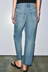 Jeans de tiro medio con corte recto y largo al tobillo. Presentan diseño de cinco bolsillos, cierre frontal con cremallera y botón, y ruedo deshilachado.