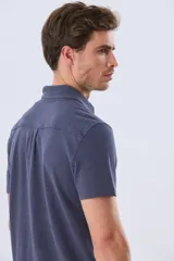 Camisa de piqué lisa color celeste, de manga corta, con cuello camisero y cierre frontal de botones oscuros.
