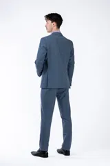 Ambo de corte slim fit compuesto por saco de dos botones con solapa clásica y pantalón de vestir a juego, en color azul con textura sutil.