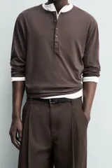 Pantalón chino de corte wide fit confeccionado en tejido de algodón. Presenta pliegues frontales, bolsillos laterales y bolsillos traseros de vivo, con cierre frontal de cremallera y botón.