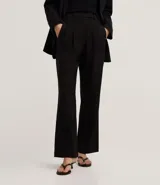 Pantalón de sastrería corte recto confeccionado en crepé, con pliegues delanteros y cintura con detalle cruzado. Presenta un diseño estructurado y elegante.