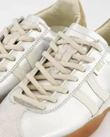 Championes de estilo retro con acabado metalizado plateado, detalles en cuero color crema y suela de goma color caramelo. Presentan cordones al tono y refuerzo en el talón.