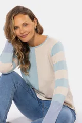 Buzo de tejido fino confeccionado en algodón, con diseño de bloques de color y rayas. Presenta un bloque azul claro en el hombro izquierdo, un bloque beige en el centro y rayas horizontales beige y azul claro en el hombro y brazo derechos. La manga izquierda es de color lila.