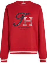 Buzo rojo de algodón con cuello redondo y mangas largas. Presenta un estampado gráfico en el pecho con las letras "TH" en azul marino con estrellas blancas y blanco con rayas rojas, junto con la leyenda "All American Classics New York City". Los puños y el bajo son acanalados con rayas blancas en contraste.