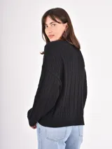 Buzo de tejido de punto con diseño de trenzas verticales, cuello redondo, mangas largas y puños acanalados.