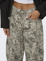 Pantalón de tiro alto con silueta barrel, más amplia en la rodilla y entallada hacia el ruedo, con estampa de efecto camuflado en tonos grises y verdosos.