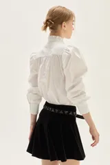 Falda corta de terciopelo negro con diseño ajustado en la cadera y volado en el ruedo.