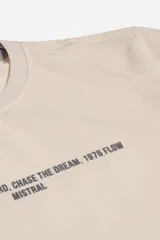 Remera de manga larga en color beige con textura acanalada sutil. Presenta una estampa frontal con texto en color gris oscuro y un ajuste regular cómodo.