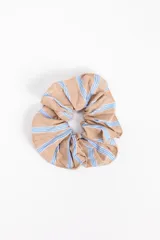 Scrunchie de tela color beige con diseño de rayas finas celestes.