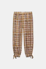 Pantalón bombacho de tiro bajo, con estampado a cuadros en tonos marrones y amarillos. Presenta bolsillos laterales ocultos y bajo acabado en lazada ajustable.