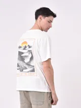 Remera de manga corta color beige claro, con cuello redondo y un pequeño estampado de un sol amarillo con texto en el pecho.