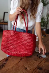 Bolso tipo tote de cuero vacuno, completamente trenzado a mano. El color es marrón oscuro, casi chocolate. Posee dos asas de hombro trenzadas.