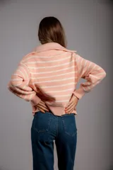 Buzo de punto color beige con rayas horizontales blancas, cuello polo con cierre de cremallera y mangas largas.