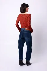 Top de manga larga con diseño de hombros descubiertos y estampado de letras repetidas en color rojo sobre fondo marrón.