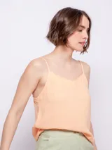 Top color durazno de breteles finos y escote con terminación ondulada.