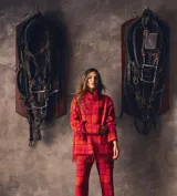 Sweater oversize de lana natural, color rojo con estampado cuadrillé. Presenta cuello alto, mangas largas y detalles de flecos torneados en el dobladillo y los puños.