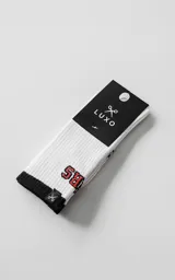 Medias de caña media color blanco con detalle de borde superior y puntera en negro. Presentan un estampado con letras en color rojo y una pequeña etiqueta textil con el logo de la marca en el borde superior.