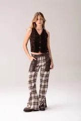Pantalón de tiro medio con diseño de cuadros tartán en tonos marrón, blanco y negro, combinado con detalles de cuero en la parte superior y grandes bolsillos frontales.