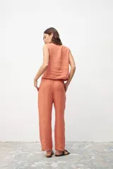Pantalón de lino color ocre, de corte recto y tiro medio, con pinzas frontales y cierre de botón y cremallera.