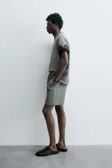 Bermuda de algodón color beige claro, corte relajado (relaxed fit), con cintura elástica ajustable mediante cordón y bolsillos laterales y trasero de plastrón.