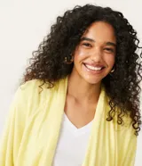 Cardigan alargado en tejido de punto color amarillo, con ribana en los puños y barra redondeada.