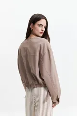 Campera verde militar sin cuello, con elástico y cinto regulable en la cintura, bolsillos amplios y cierre frontal.