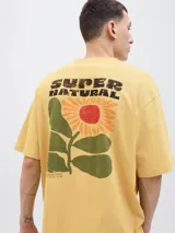 Remera color crema con estampado de flor y texto 'Super Natural' en la espalda.