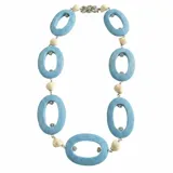 Collar Fahoma de diseño exclusivo, elaborado con grandes piezas de madera celestes de forma ovalada, intercaladas con cuentas de resina beige y pequeñas cuentas con cristales incrustados. Cuenta con un cierre vintage de cristal plateado.