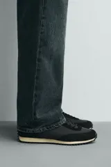 Zapatilla de estilo retro con cordones, confeccionada en una combinación de materiales textiles y piezas de cuero con acabado serraje. Presenta una suela dentada en contraste de color.