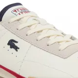 Championes Lacoste modelo Aura, de diseño retro con base de cuero color blanco, detalles en azul marino en el talón y lengüeta, franja lateral roja y suela de goma color caramelo.