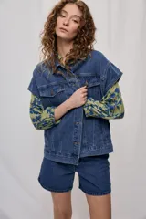 Chaleco oversize de jean negro, con cuello camisero, cierre frontal con botones metálicos y bolsillos delanteros.