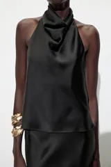 Top blanco satinado con cuello halter y escote fluido. Cierre en la espalda con botones.