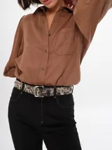 Cinturón de cuero con estampado animal print en tonos blanco y negro, con hebilla metálica plateada.