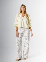 Pantalón wide leg de denim rígido con estampado floral chintz en tonos amarillo y rosa pastel sobre base blanca.